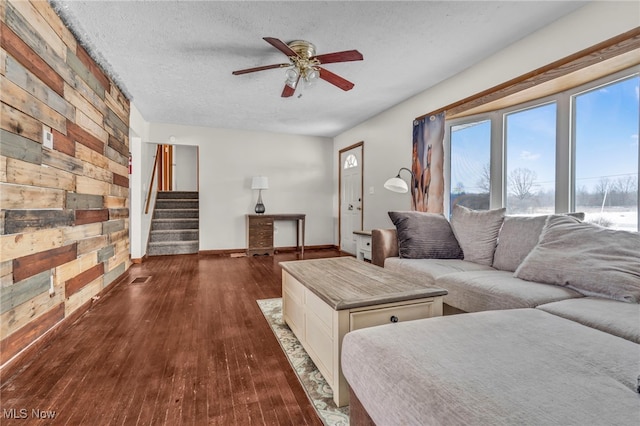 living room with a textured ceiling, ceiling fan, and dark hardwood / wood-style flooring