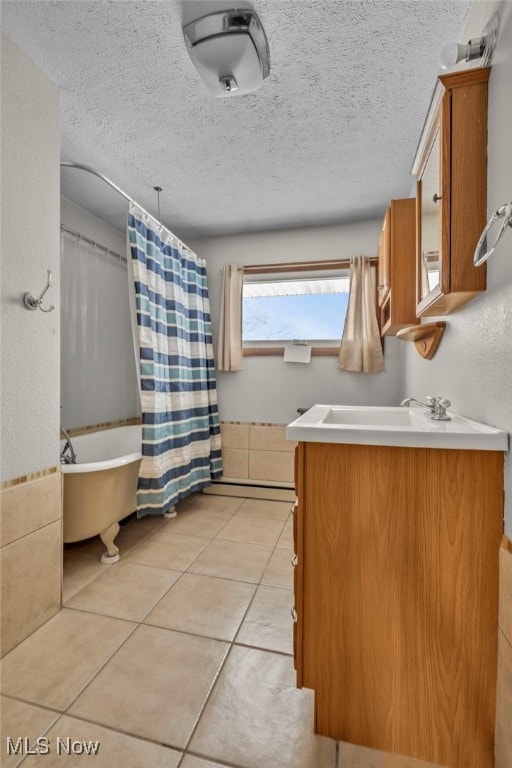 bathroom with baseboard heating, a textured ceiling, shower / bathtub combination with curtain, tile patterned floors, and vanity