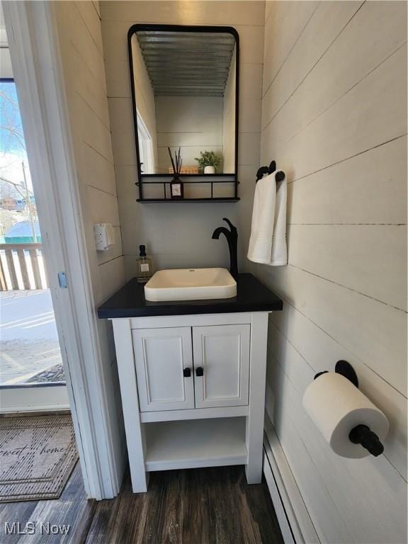 bathroom featuring hardwood / wood-style flooring, vanity, and wood walls