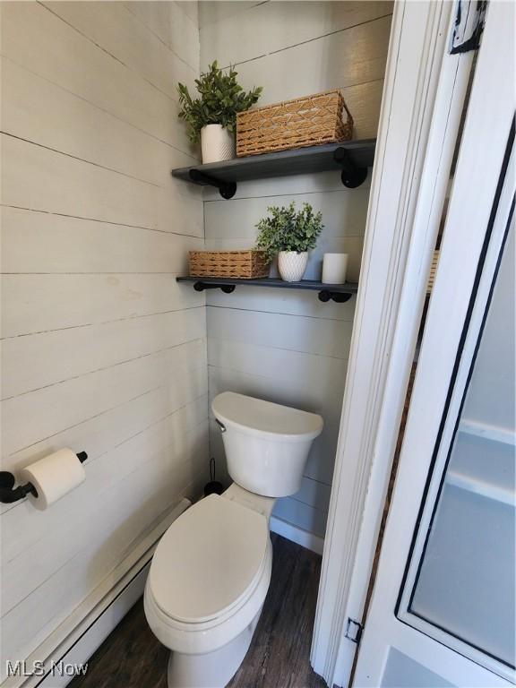 bathroom with toilet, wood walls, and hardwood / wood-style floors