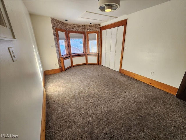 unfurnished room featuring carpet flooring and brick wall