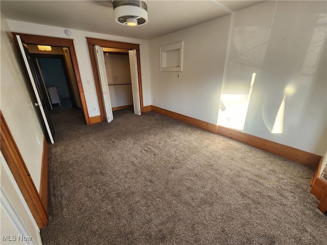 unfurnished bedroom featuring a closet and dark carpet