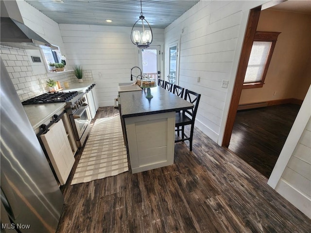 kitchen with hanging light fixtures, dark hardwood / wood-style flooring, a breakfast bar, wooden walls, and high end stove