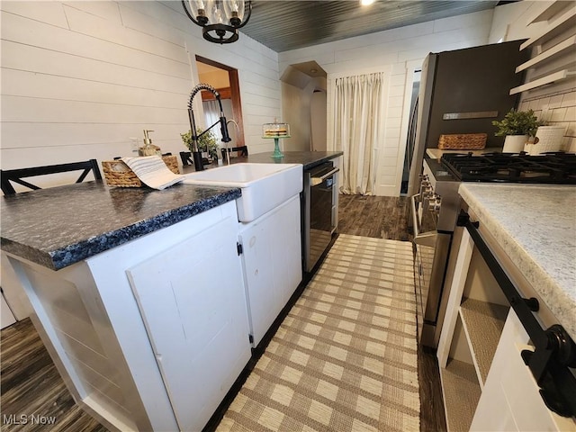 kitchen featuring hardwood / wood-style flooring, white cabinetry, sink, dishwashing machine, and high end stainless steel range oven