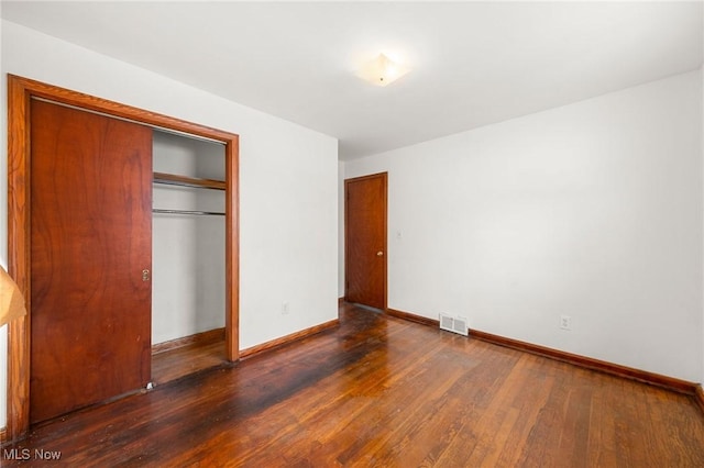 unfurnished bedroom featuring dark hardwood / wood-style floors and a closet