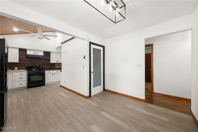 kitchen featuring vaulted ceiling, light wood-type flooring, white cabinets, black appliances, and decorative backsplash