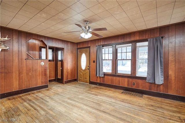 entryway featuring light wood-type flooring, wooden walls, and ceiling fan