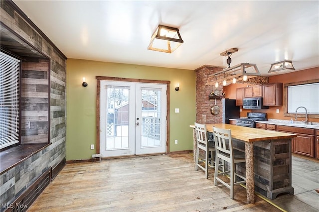 kitchen featuring wooden counters, stainless steel appliances, french doors, sink, and hanging light fixtures