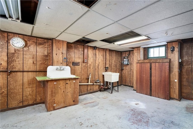 basement with sink, wood walls, and a paneled ceiling