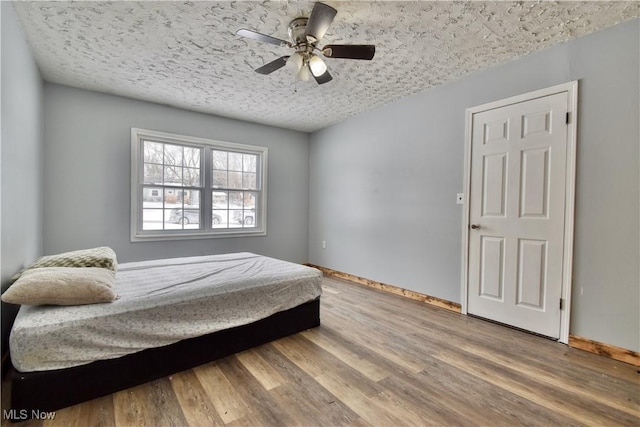 bedroom featuring ceiling fan, a textured ceiling, and hardwood / wood-style flooring