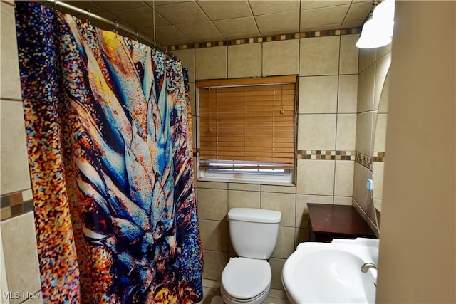 bathroom featuring sink, tile walls, and toilet