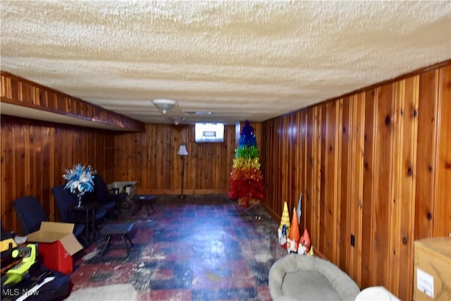 interior space featuring a textured ceiling and wood walls