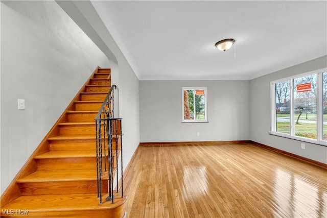 stairs with hardwood / wood-style floors and a healthy amount of sunlight