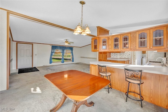 kitchen featuring kitchen peninsula, hanging light fixtures, sink, ornamental molding, and a breakfast bar area