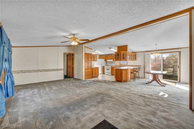 unfurnished living room with ceiling fan with notable chandelier, carpet flooring, and crown molding