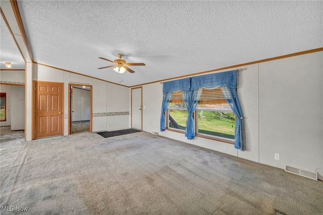 unfurnished living room with vaulted ceiling, crown molding, carpet floors, and a textured ceiling