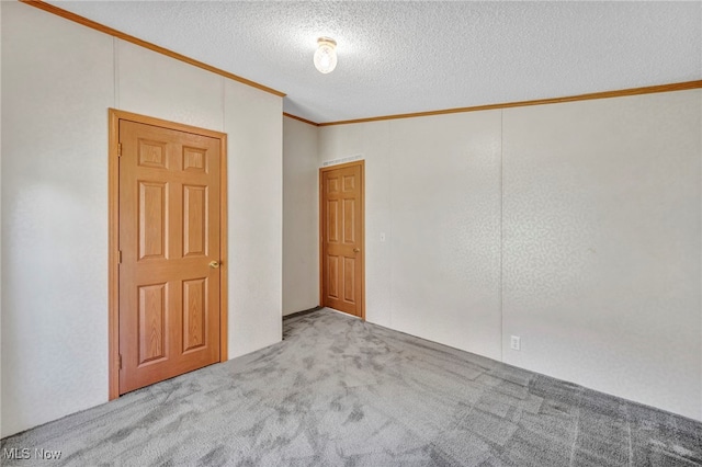 carpeted empty room with a textured ceiling and crown molding