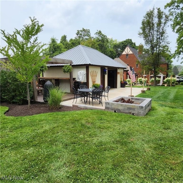 rear view of property featuring an outdoor fire pit, a patio, and a lawn