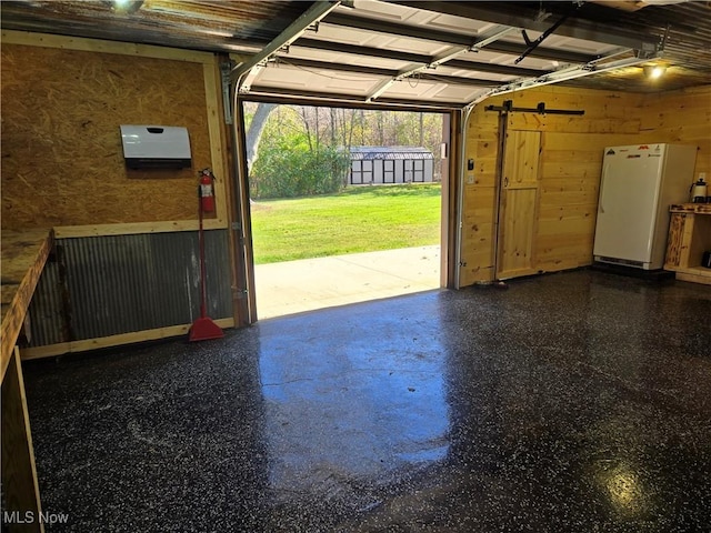 garage with white refrigerator and wood walls