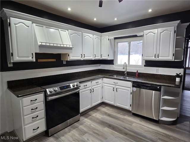 kitchen featuring sink, premium range hood, stainless steel appliances, light hardwood / wood-style floors, and white cabinets