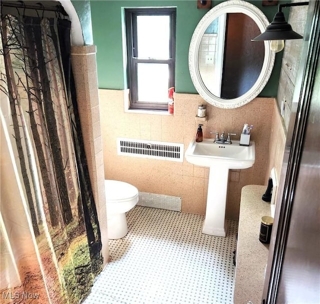 bathroom featuring toilet, sink, and tile walls