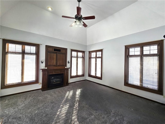 unfurnished living room featuring ceiling fan, a wealth of natural light, and dark carpet