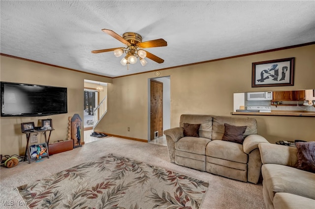 living room with ceiling fan, ornamental molding, carpet flooring, and a textured ceiling