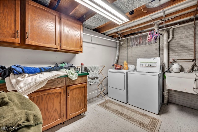 clothes washing area with cabinets, washing machine and dryer, and sink