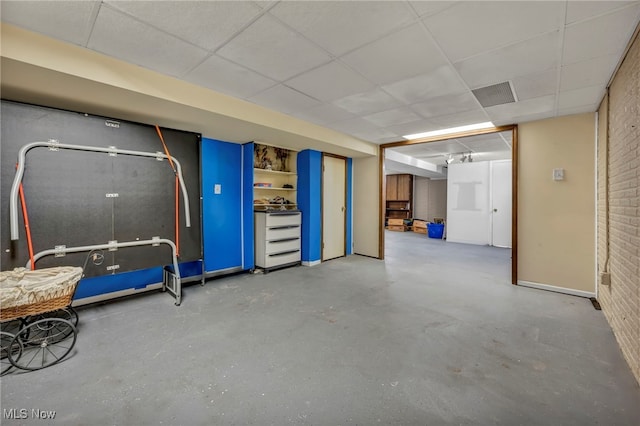 basement with a drop ceiling and brick wall