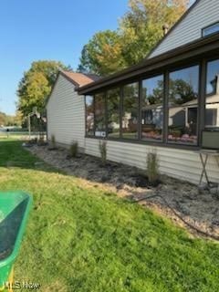 view of side of home featuring a sunroom and a lawn