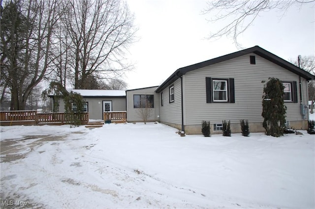 snow covered back of property featuring a deck