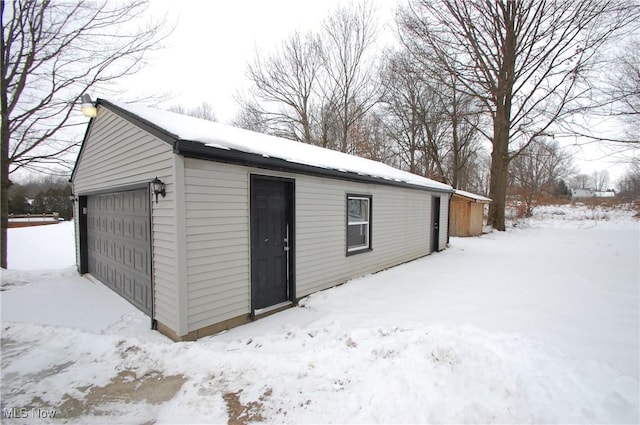 snow covered structure featuring a garage