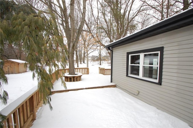 snow covered deck featuring a storage shed