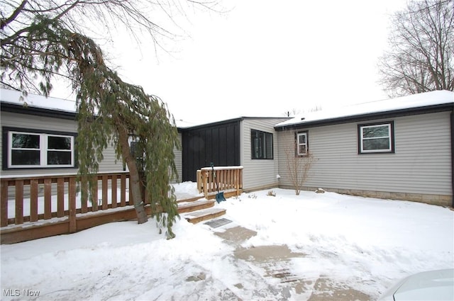 snow covered house featuring a wooden deck