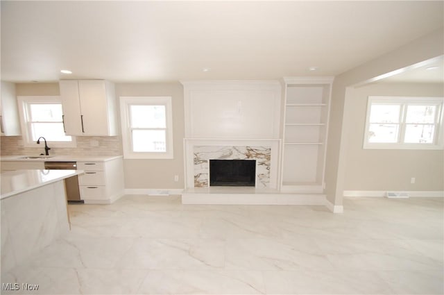 unfurnished living room with sink and a high end fireplace