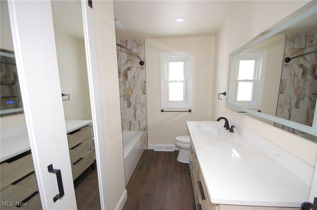 full bathroom featuring tiled shower / bath combo, vanity, and toilet