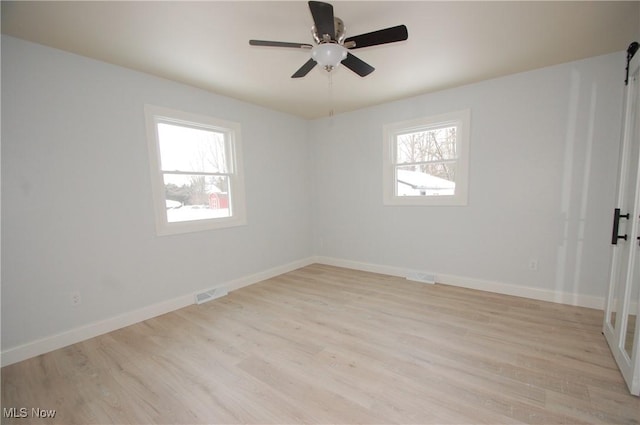 empty room featuring a wealth of natural light, ceiling fan, and light hardwood / wood-style flooring