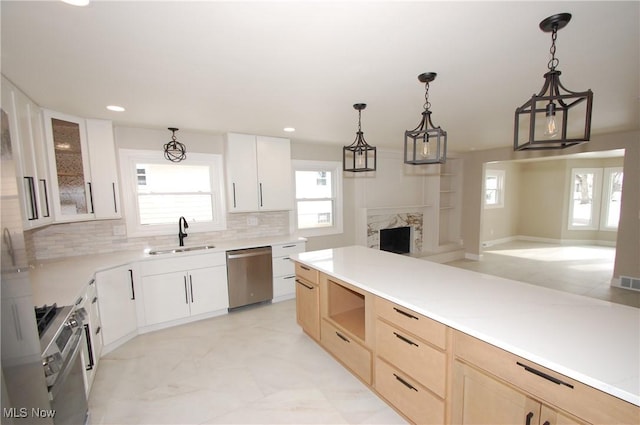 kitchen featuring white cabinetry, sink, stainless steel appliances, and hanging light fixtures