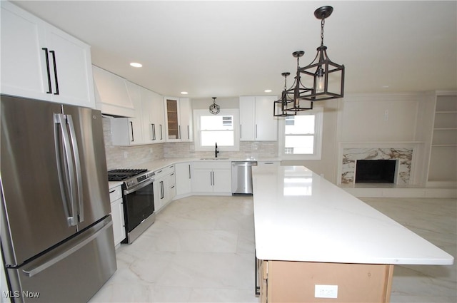 kitchen with sink, appliances with stainless steel finishes, white cabinetry, a center island, and custom range hood