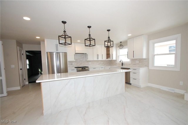 kitchen with stainless steel appliances, a center island, pendant lighting, and white cabinets