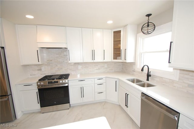 kitchen with appliances with stainless steel finishes, tasteful backsplash, white cabinetry, sink, and hanging light fixtures