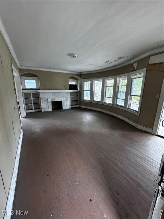 unfurnished living room featuring crown molding, dark hardwood / wood-style floors, and a brick fireplace