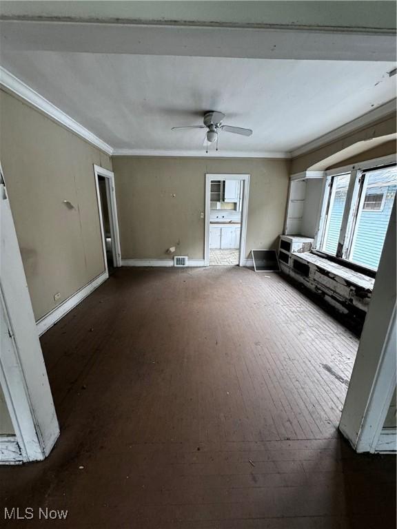 unfurnished living room featuring ceiling fan, dark hardwood / wood-style flooring, and crown molding