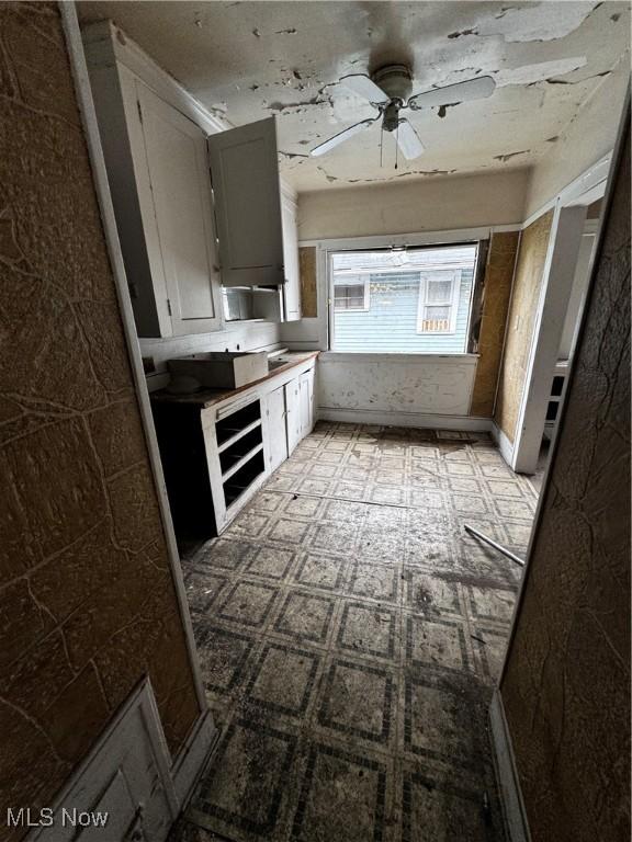 kitchen with ceiling fan and white cabinets