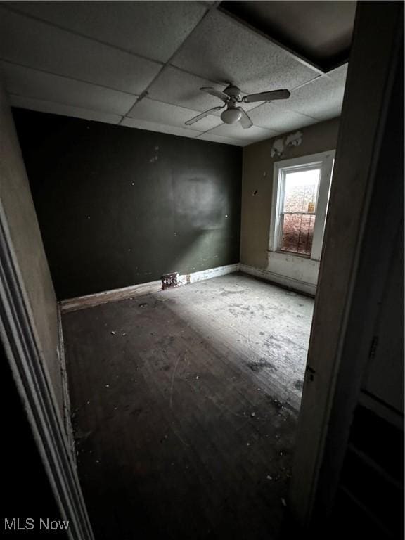 empty room featuring a drop ceiling and ceiling fan