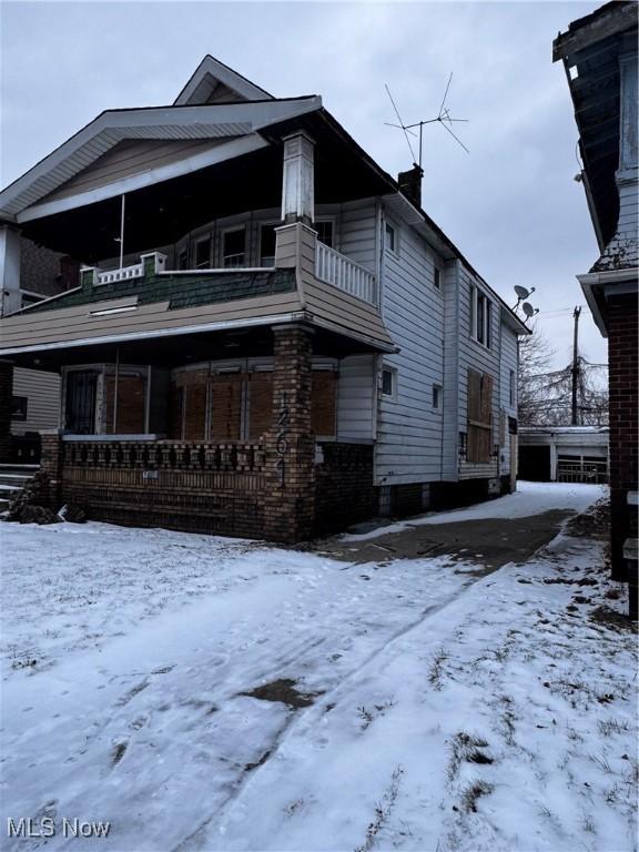 snow covered back of property with a balcony