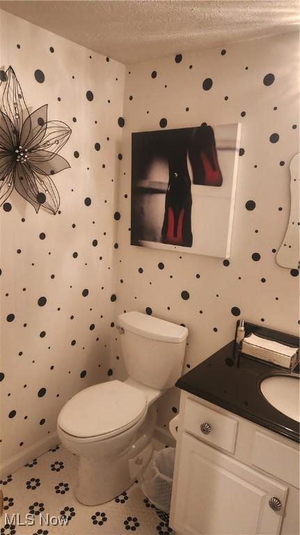 bathroom featuring vanity, toilet, tile patterned flooring, and a textured ceiling