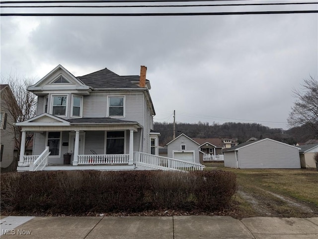 view of front facade featuring an outbuilding, a porch, and a garage