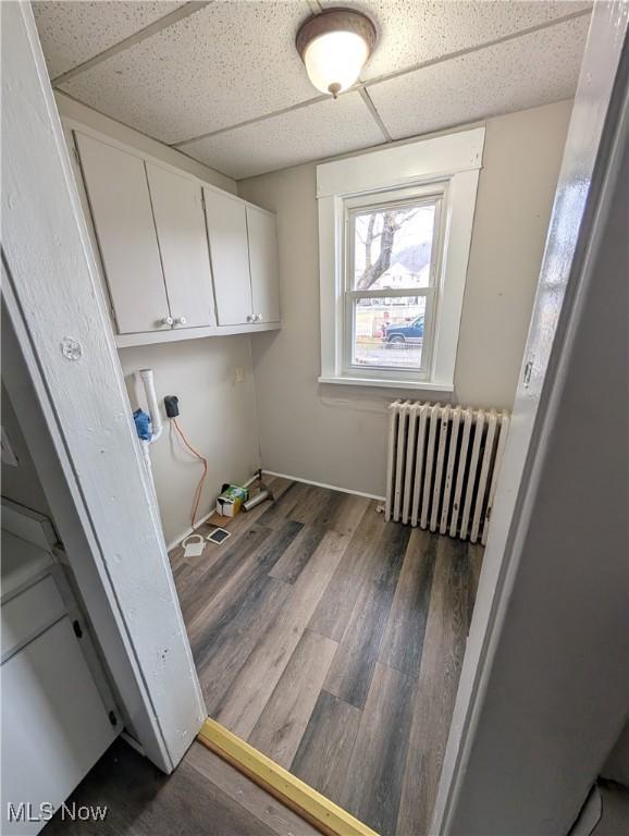 clothes washing area featuring radiator and dark hardwood / wood-style floors