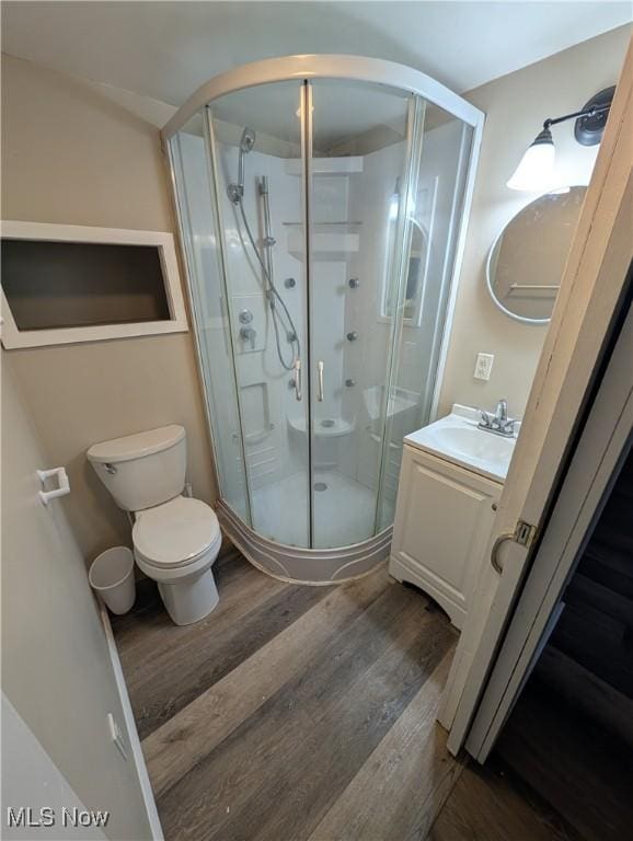 bathroom featuring toilet, hardwood / wood-style floors, vanity, and a shower with shower door